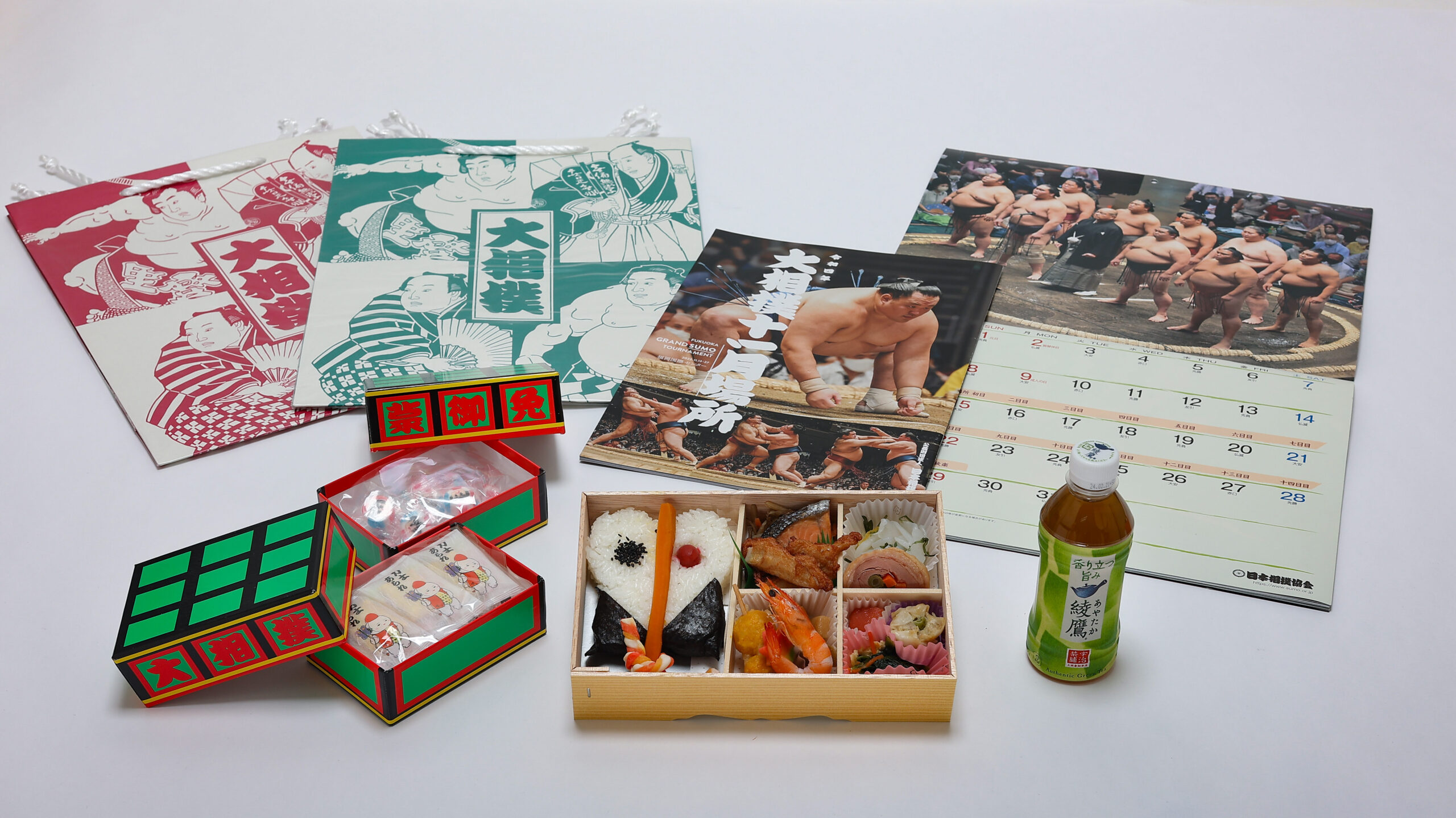 軍配幕ノ内弁当 お茶 大相撲カレンダー 九州場所パンフレット 明け荷の箱に入ったお菓子（力士柄の金太郎飴・カレー味のあられ） 相撲柄紙袋 のセットです。